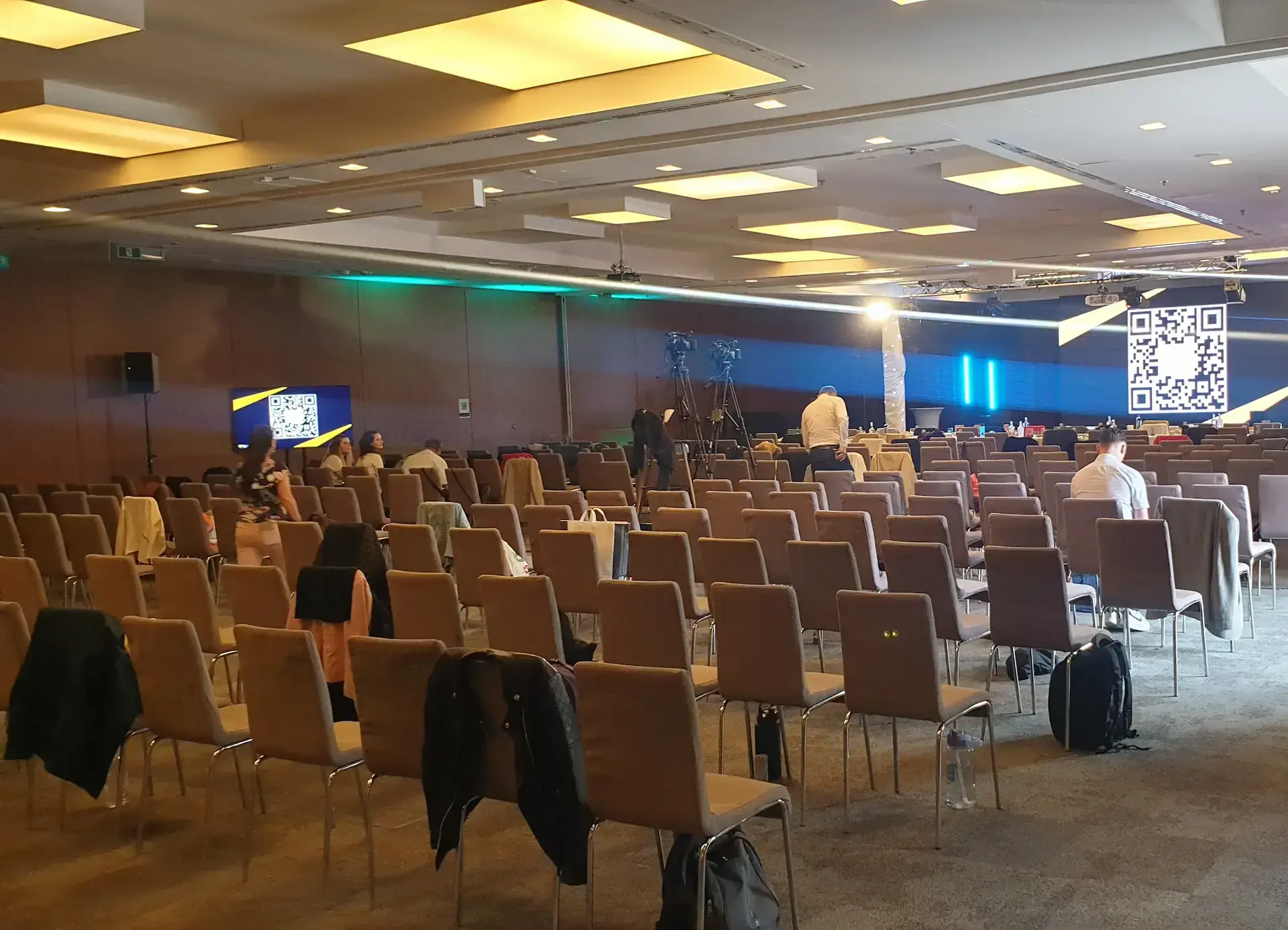 Modern konferencia helyszín felállítása 200 fős színházas ülésrenddel és színpaddal háttérben dolgozó csapattal