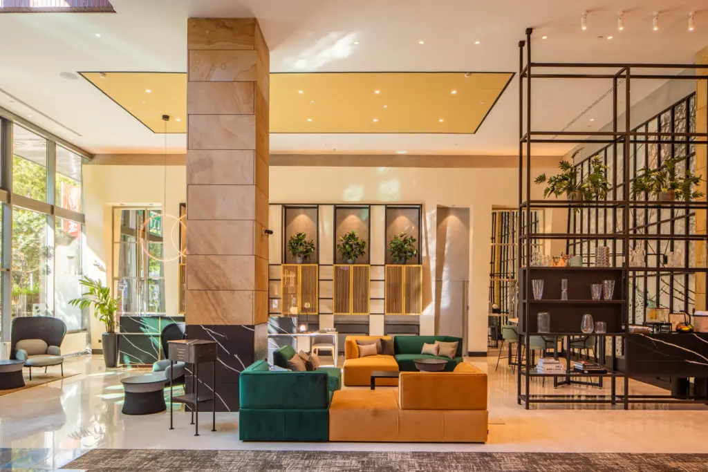 Crowne Plaza Budapest modern lobby smaragdzöld és narancssárga bútorokkal és természetes fénnyel