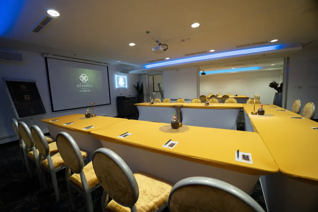 Hotel Divinus konferenciaterem, U-alakú ülésrend, sárga asztalok, projektor, 30-40 fő meeting