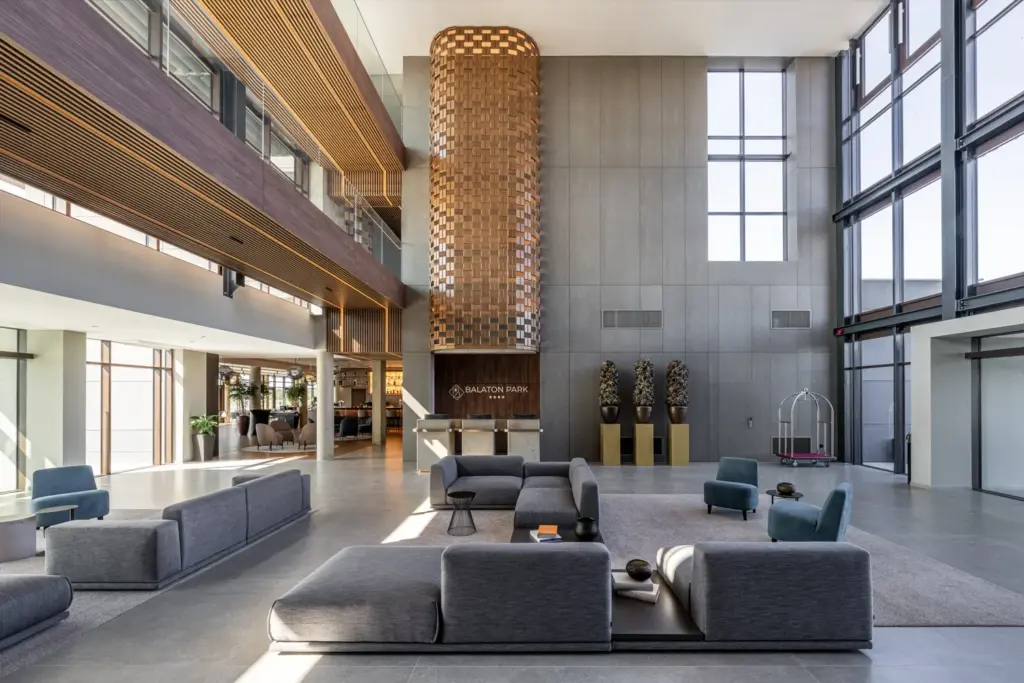Modern hotel lobby dupla belmagassággal, fa csillárral és kortárs dizájnnal