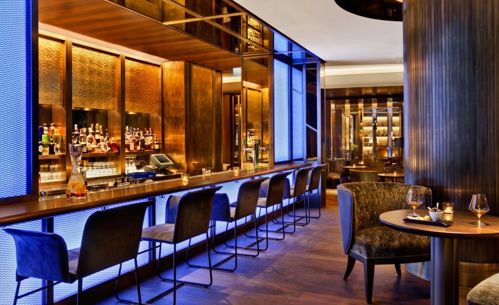 Luxus hotelbar kék LED világítással, dió bárpulttal és bársony székekkel