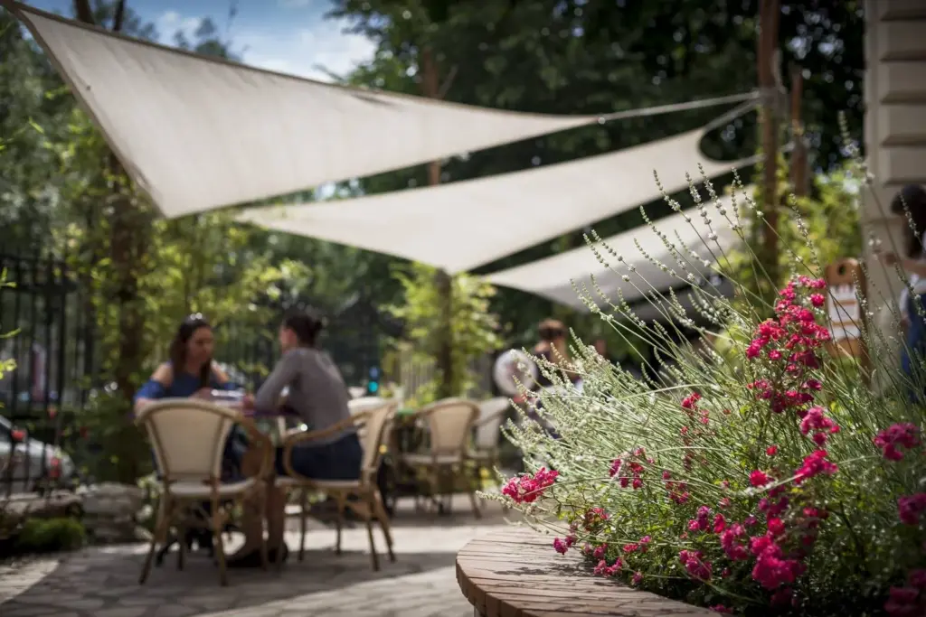 Árnyékolt terasz virágokkal és napvitorlával zöld környezetben