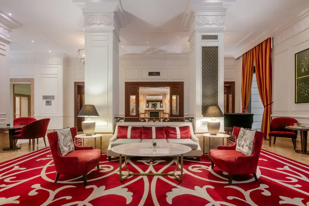 Corinthia Budapest lobby lounge, elegáns várakozó, piros fotelek, fehér oszlopok, luxus pihenőzóna