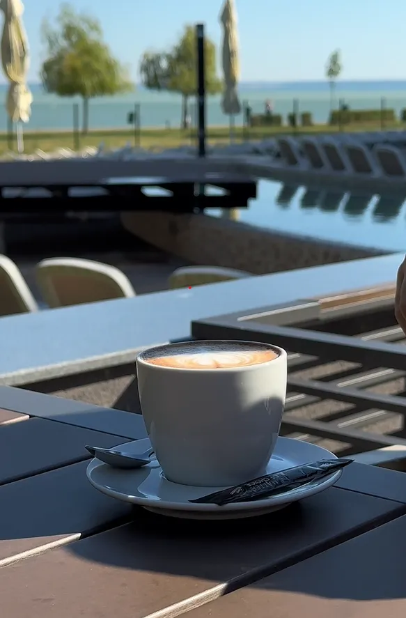 appuccino a Prémium Hotel Panoráma outdoor teraszán, ahol napozóágyak és közvetlen Balaton-parti panoráma várja a pihenni vágyókat