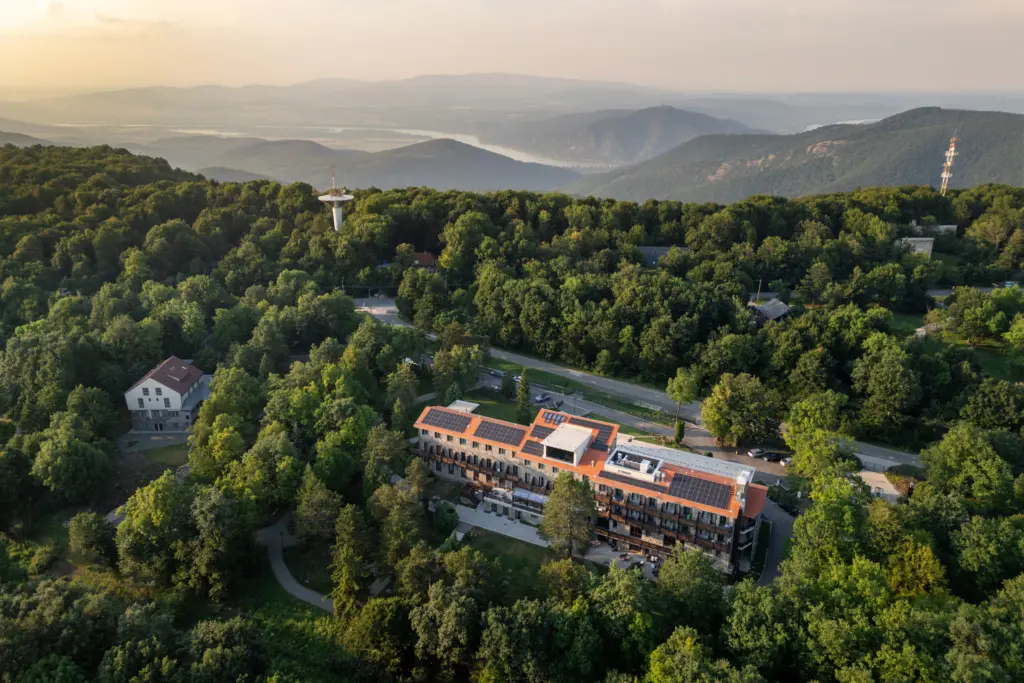 Légi felvétel a Cardoner Hotel Dobogókőről, ahol a narancssárga hotel épület látható erdők között a Visegrádi-hegység és a Dunakanyar panorámájával