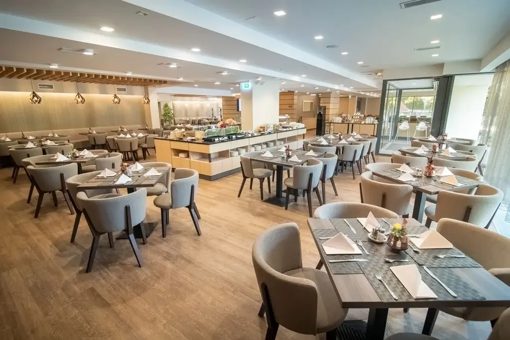 A Rubin Wellness & Conference Hotel Budapest Essence étterme, ahol modern design, svédasztalos büfé, bézs fotelok és réz csillár látható
