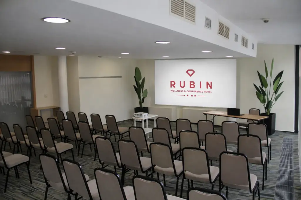 A Rubin Wellness & Conference Hotel Budapest Sirály terme színházi ültetéssel, ahol vetítővászon, projektor és bézs székek láthatók 300 négyzetméteren