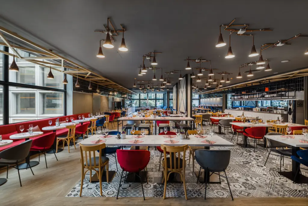 A Mercure Budapest Castle Hill The Station Hall Restaurant étterme, ahol színes székek, réz lámpák és modern gasztronómia látható kortárs magyar konyhával